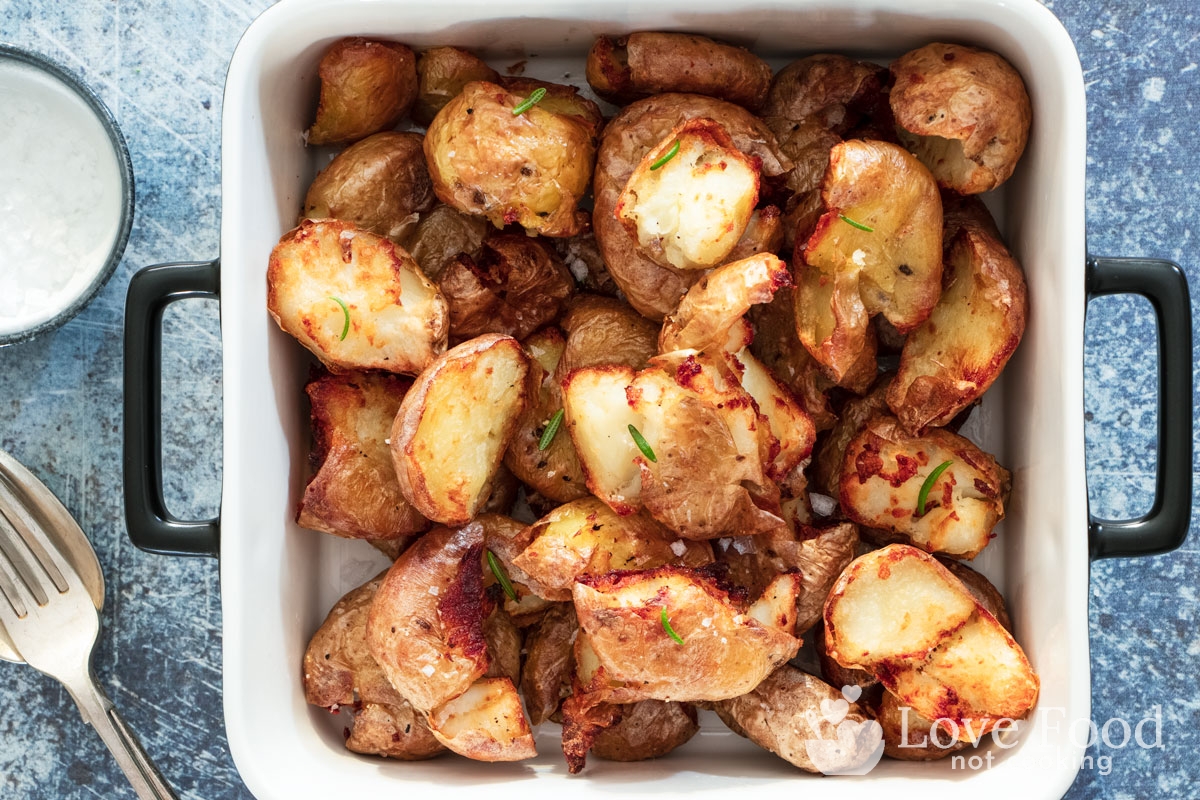 Air fryer smashed potatoes in a white serving dish. 