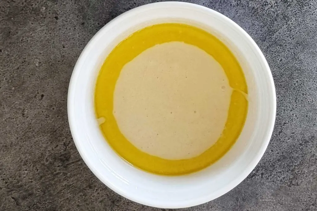 Melted butter and batter in a round white baking dish. 