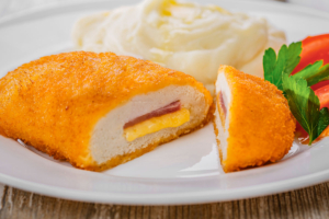 Chicken cordon bleu cut open on a white plate.