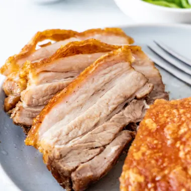 Thick slices of air fryer pork belly on a blue plate.