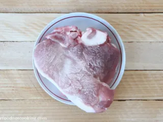 Frozen pork roast in a white bowl.