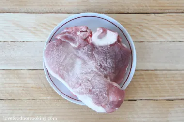 Frozen pork roast in a white bowl.