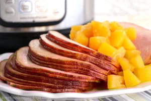 Instant Pot boneless ham on a white plate in front of an Instant Pot.