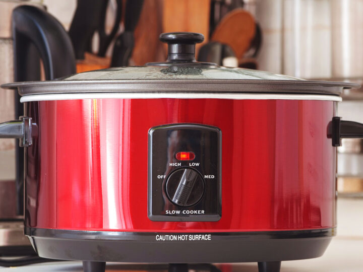 A bright red slow cooker on a kitchen bench.