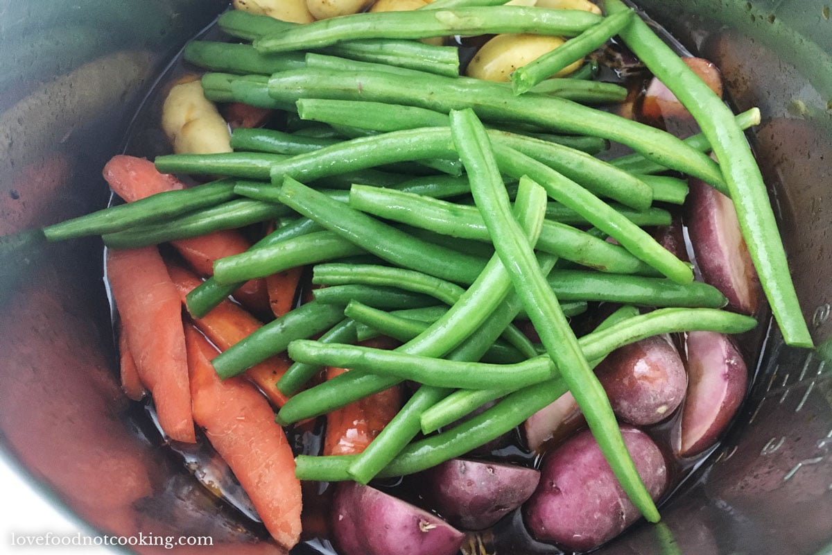 Uncooked vegetables in Instant Pot with chuck roast. 