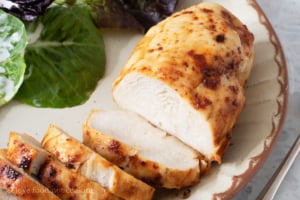 Air fried frozen chicken breast sliced on a plate with salad.