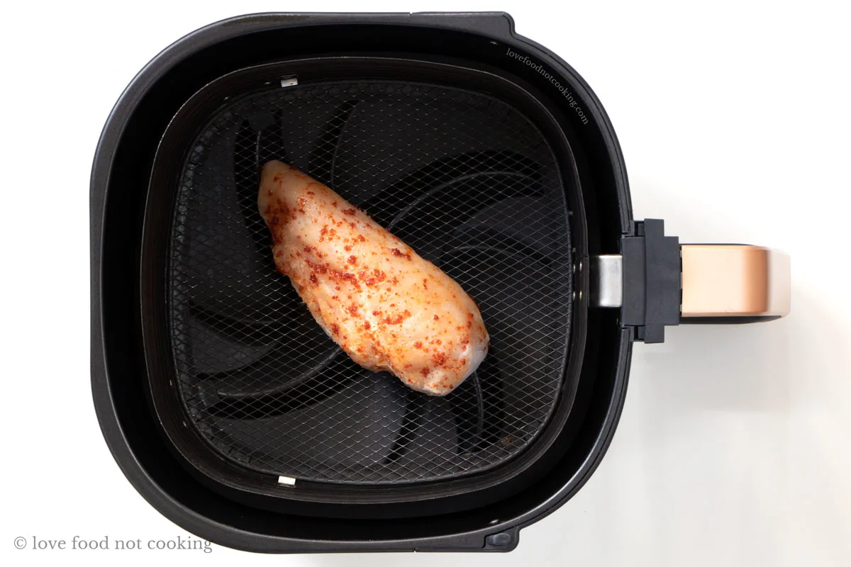 Frozen chicken breast in air fryer basket. 