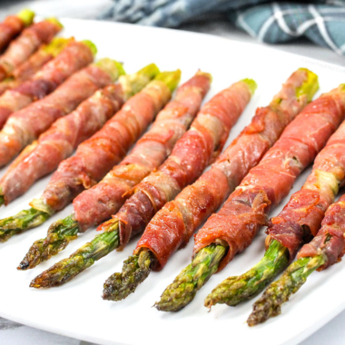 Air fryer bacon wrapped asparagus on a white plate.