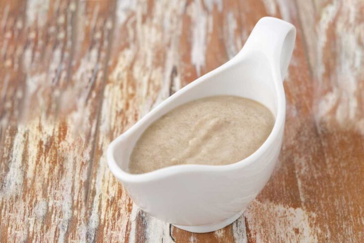 Cream of mushroom soup gravy in a white gravy boat.