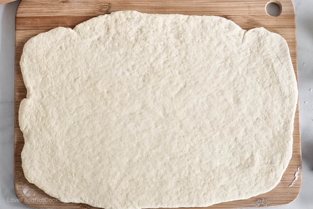 This three ingredient pizza dough rolled out on a wooden board.