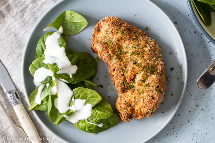 Air fryer chicken cutlet on a blue plate with salad.