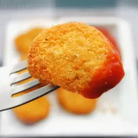 Air fryer frozen chicken nuggets on a fork with tomato sauce.
