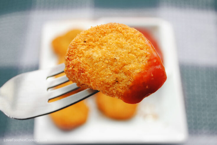 Air fryer frozen chicken nuggets on a fork with tomato sauce.