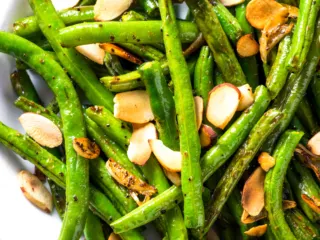 Air fryer green beans with almonds in a white bowl.