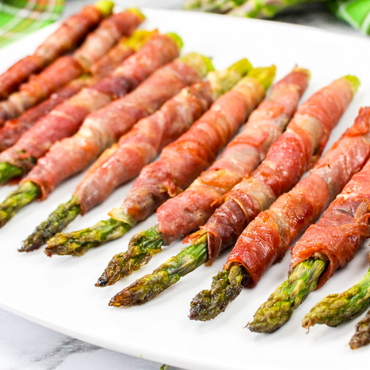 Air fryer bacon wrapped asparagus on a white plate.