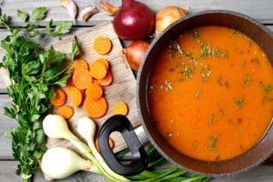 A pan of soup and raw ingredients.
