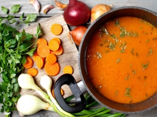 A pan of soup and raw ingredients.