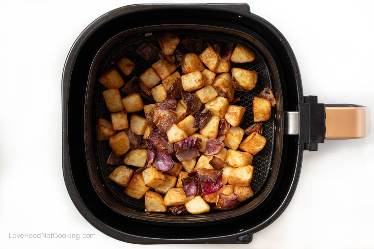 Air fried potatoes and onions in air fryer basket.