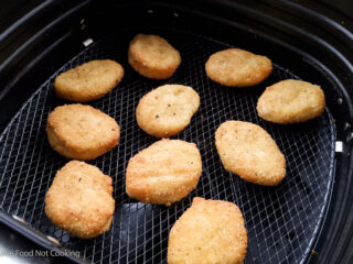Cooked chicken nuggets in air fryer basket.