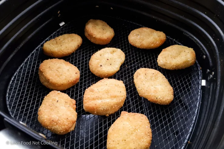 Cooked chicken nuggets in air fryer basket.