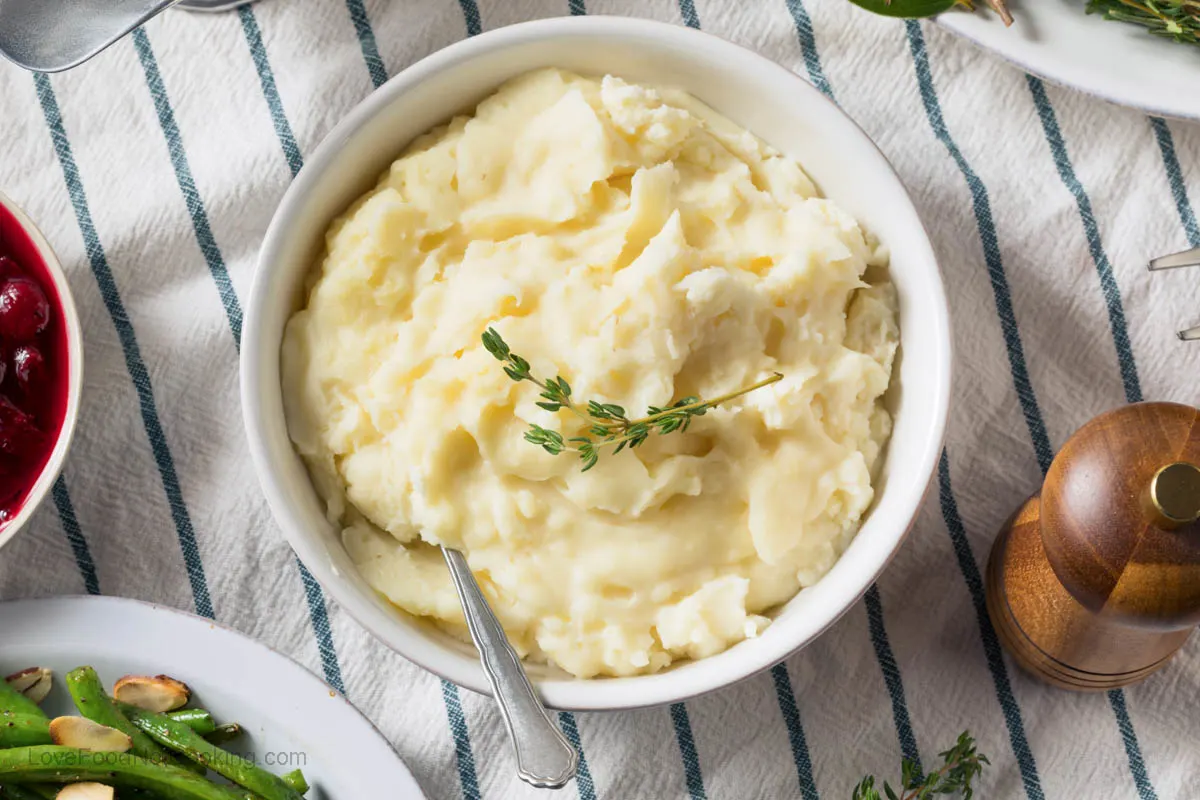 A white bowl of mashed potatoes on a table.