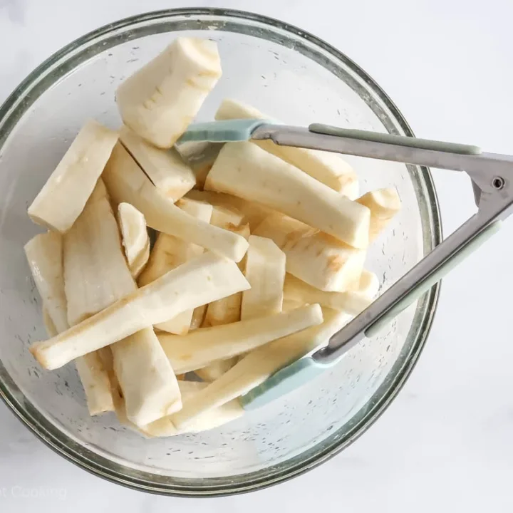Parsnip chunks in a glass bowl with oil and salt. 