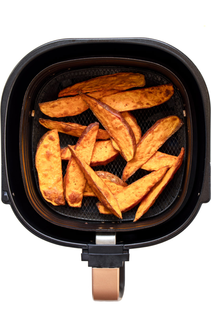 Air fried sweet potato wedges in air fryer basket.