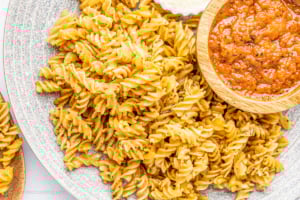 Air fryer pasta chips on a gray plate with red pepper dip.