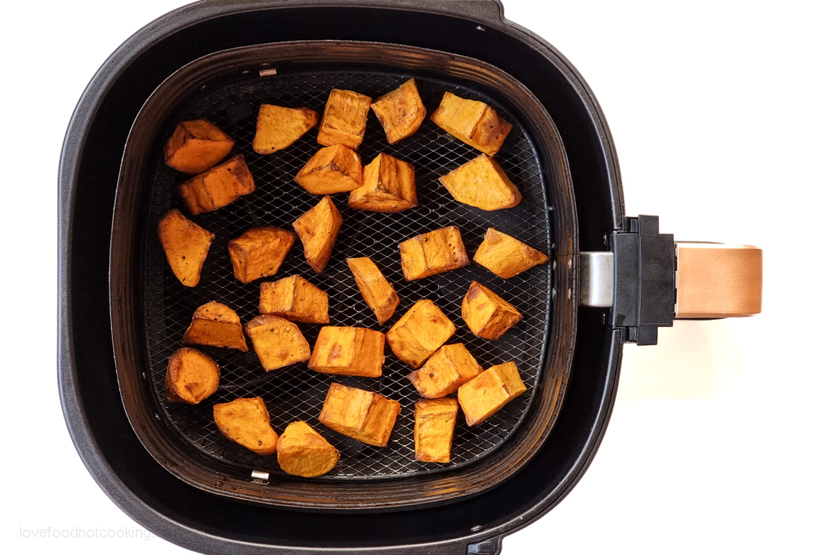 Air fried sweet potato cubes in air fryer basket.