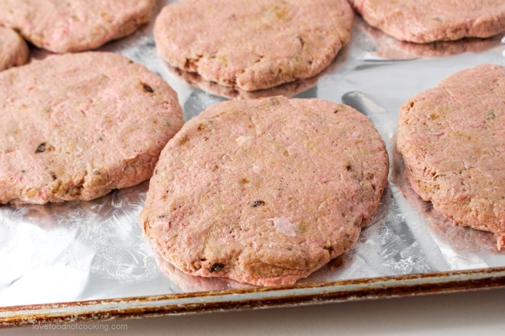 Uncooked turkey patties on a metal tray.