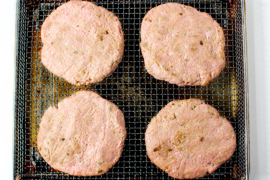 Uncooked turkey burgers in air fryer tray. 