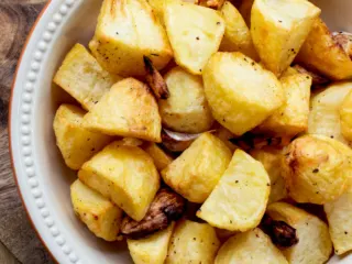 Crispy air fryer roast potatoes in a white serving dish.