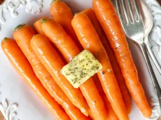 Microwave steamed carrots on a white plate.