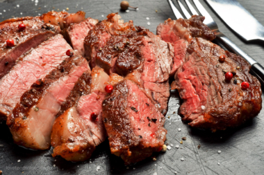 Sliced steak on a black board, showing different levels of doneness.