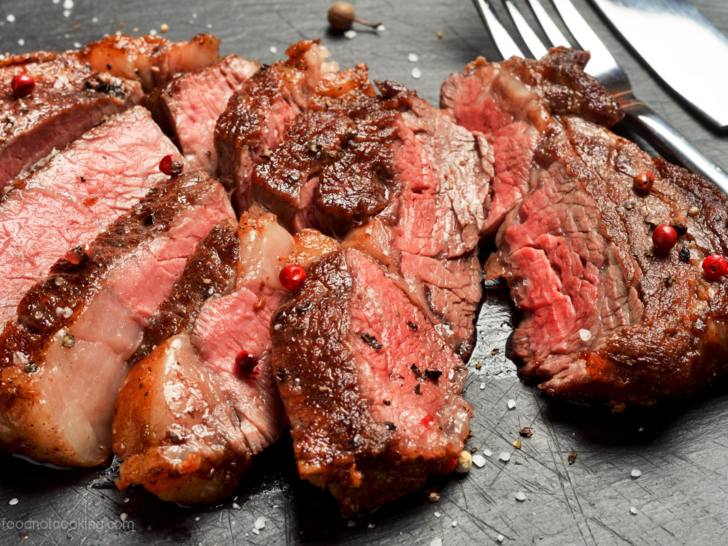 Sliced steak on a black board, showing different levels of doneness.