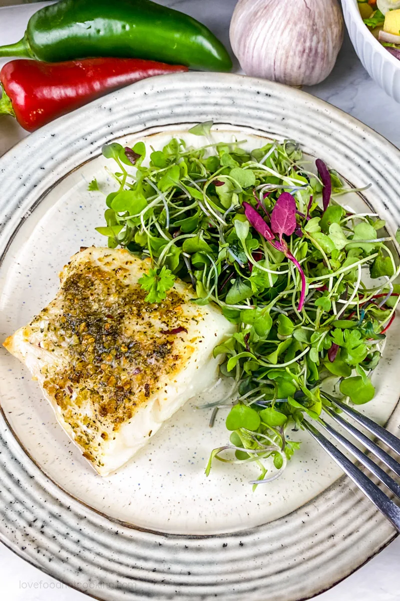 Air fried white fish on a plate with micro salad greens.