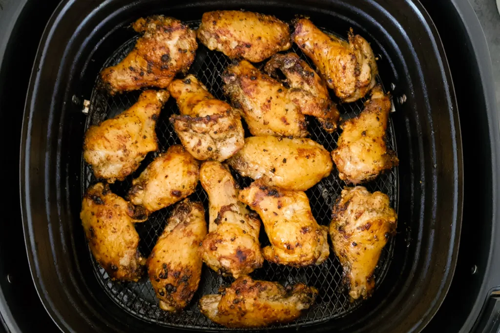 Air fried chicken wings in air fryer basket. 