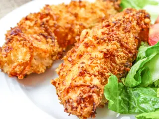 Homemade air fryer chicken tenders on a white plate.