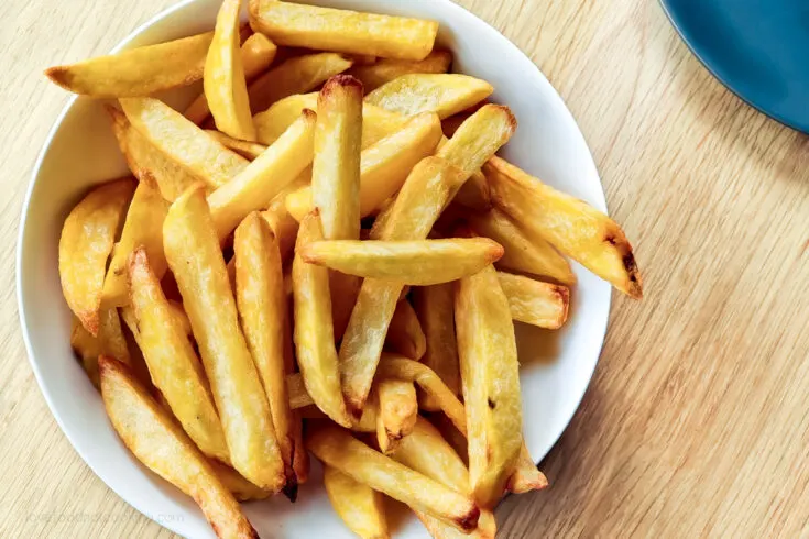 Air fryer french fries in a white bowl.