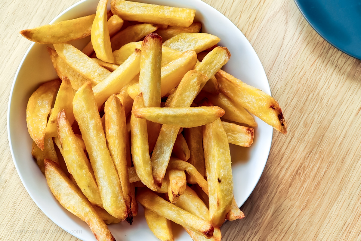 Air fryer french fries in a white bowl.