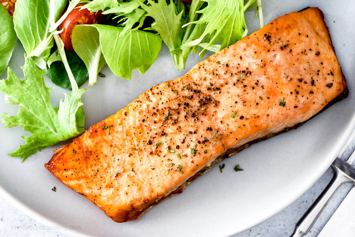 Air fryer salmon on a blue plate with salad.