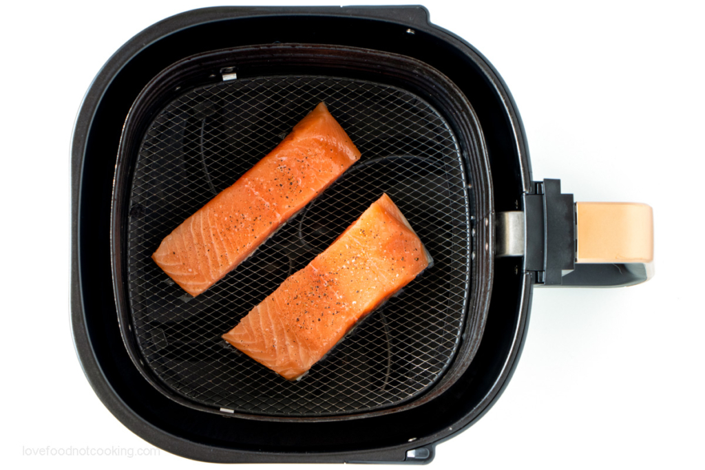 Uncooked salmon in air fryer basket. 