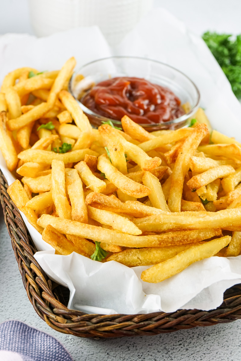 Air fried french fries in a basket with ketchup.