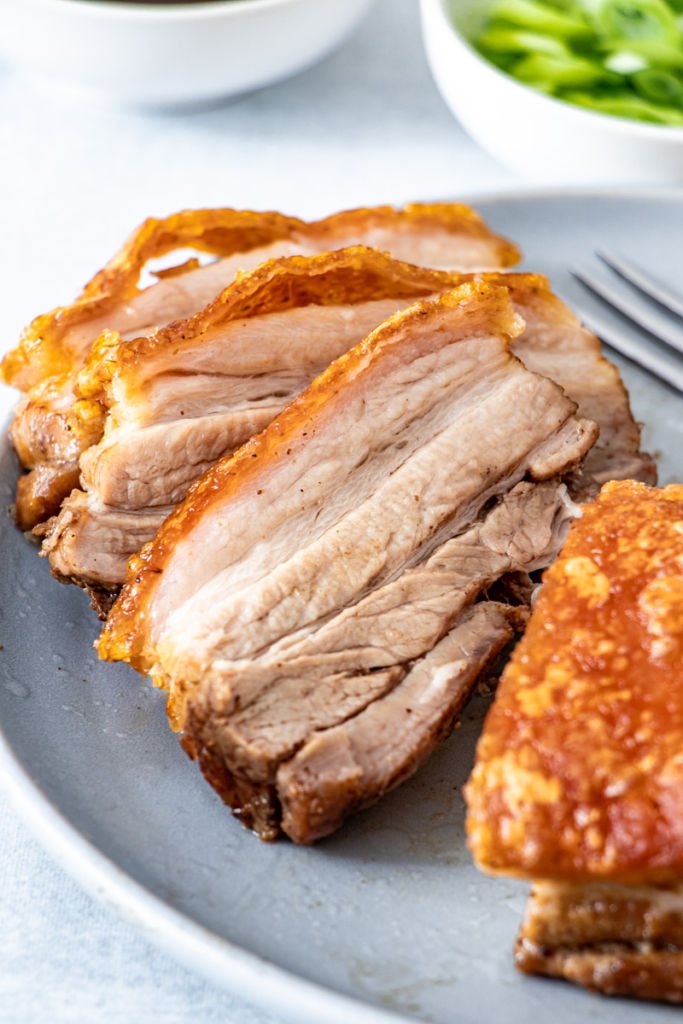 Sliced air fried pork belly on a blue plate.