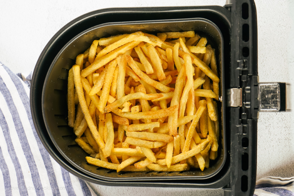 Air fried frozen french fries in air fryer basket.
