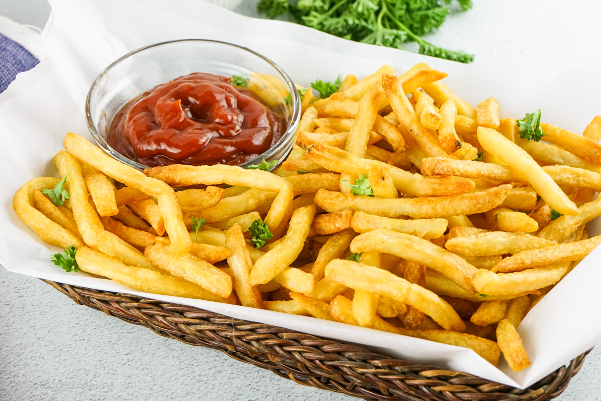 Air fryer french fries in a basket with ketchup.