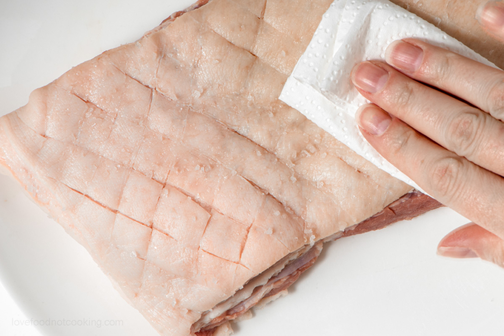 Patting the pork skin dry. 