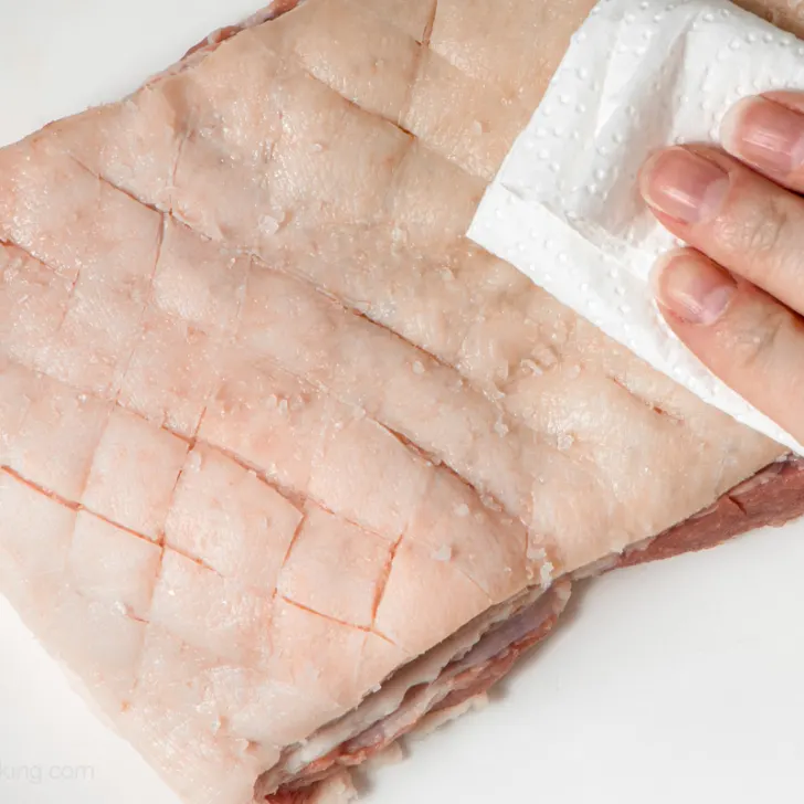 Patting the pork skin dry. 