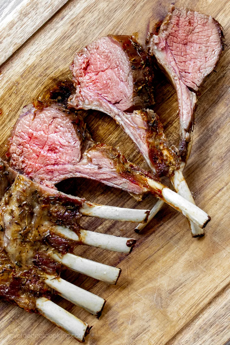 Sliced air fryer rack of lamb on a wooden board. 