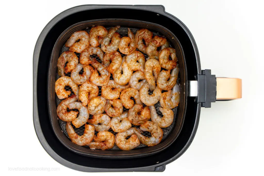 Raw shrimp in air fryer basket.